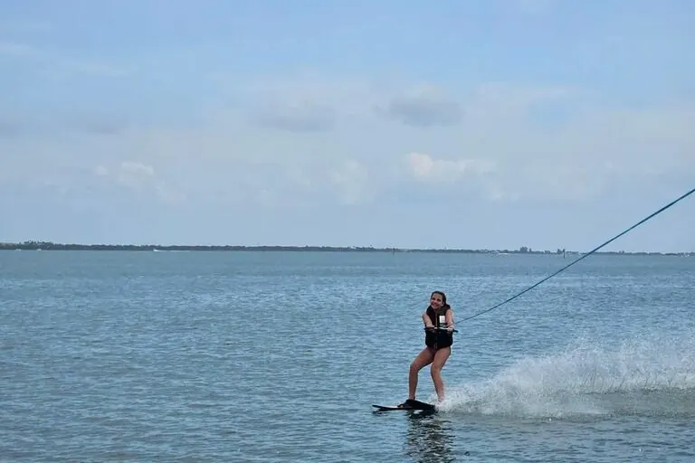 Beginner water skier rising up behind a boat on calm water
