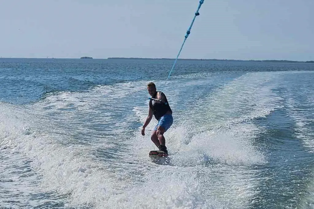 Water skier carving behind a boat on a sunny day