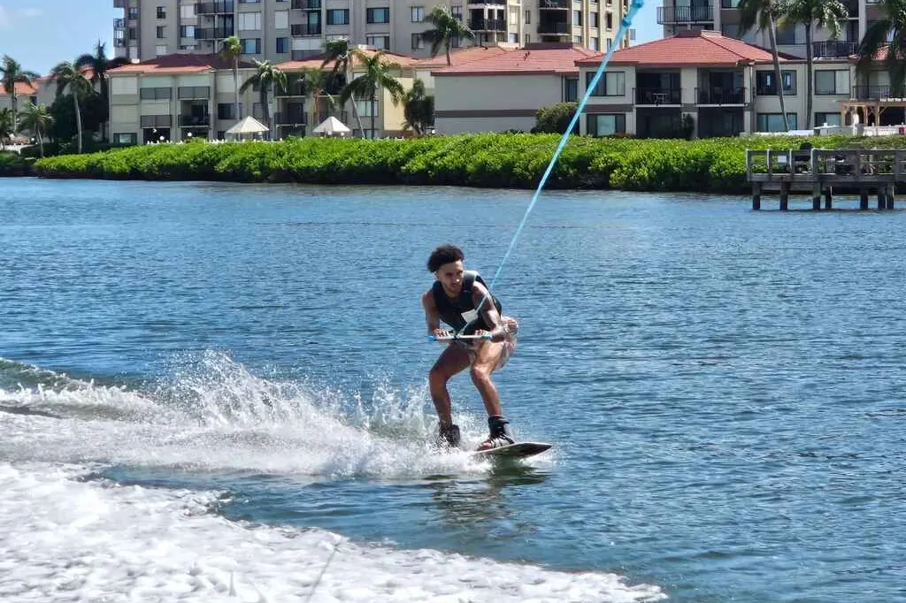 Rider on a wakeboard behind a boat on calm bay water