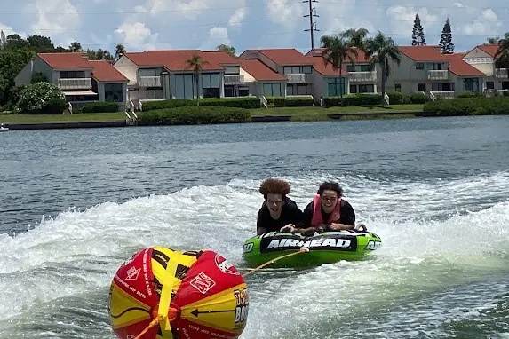 Kids laughing on a tube pulled behind a boat