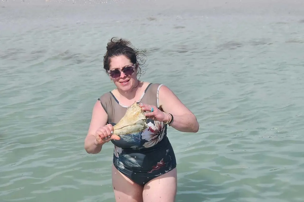 Large lightning whelk shell held up on Shell Key