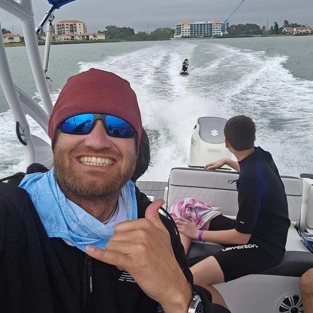 Captain Allen smiling at the stern while a guest rides the tube in the wake